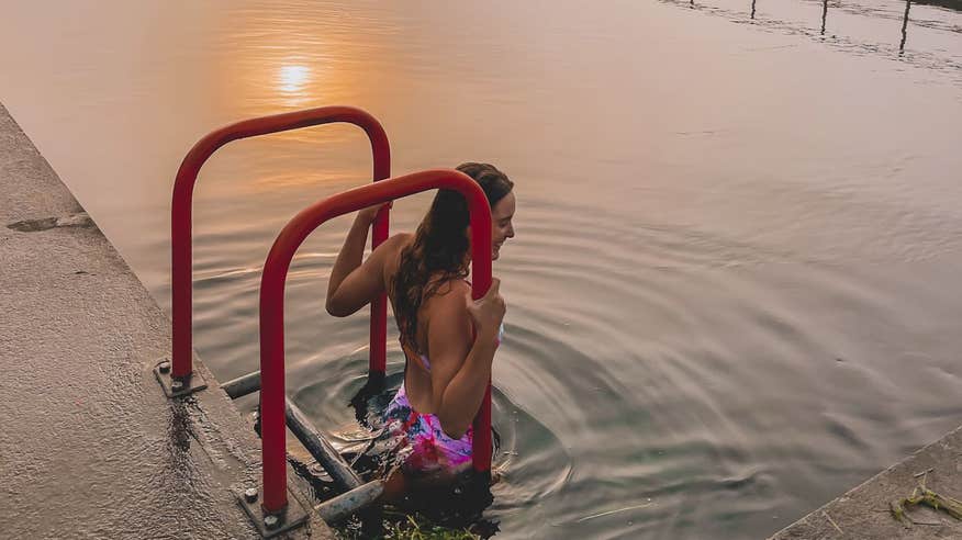 Roz Purcell standing in the water at sunrise in Banagher Outdoor Swimming Pool, Offaly