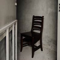 A lone chair in a small, scruffy room