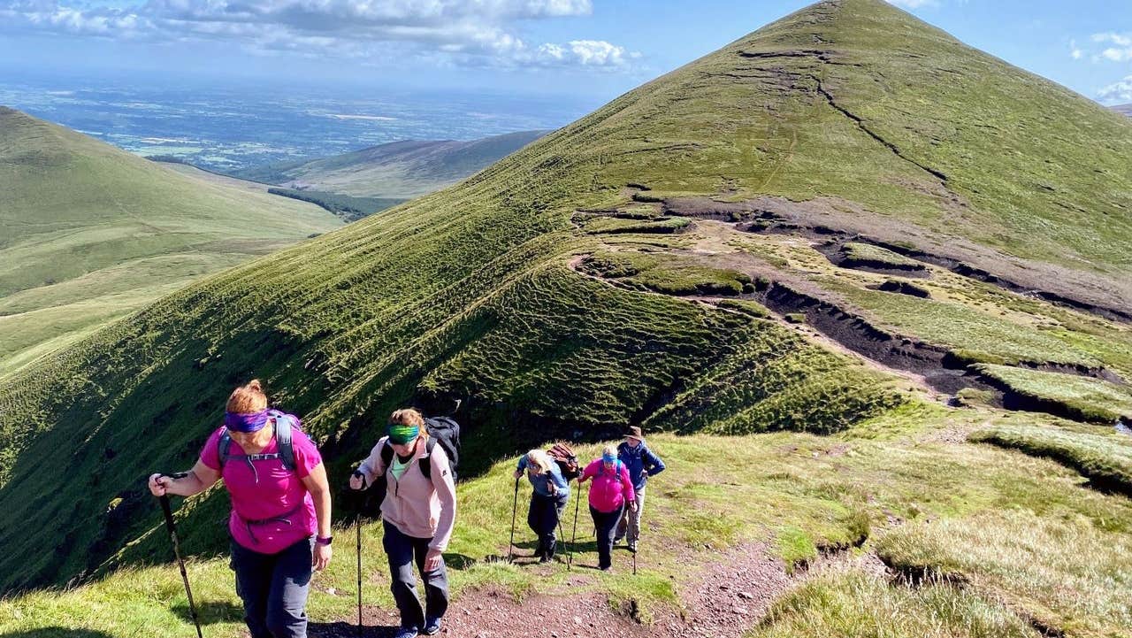 Five hikers walking up an ascent in single file