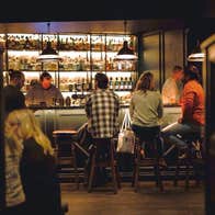 People sitting on stools at a bar in low light