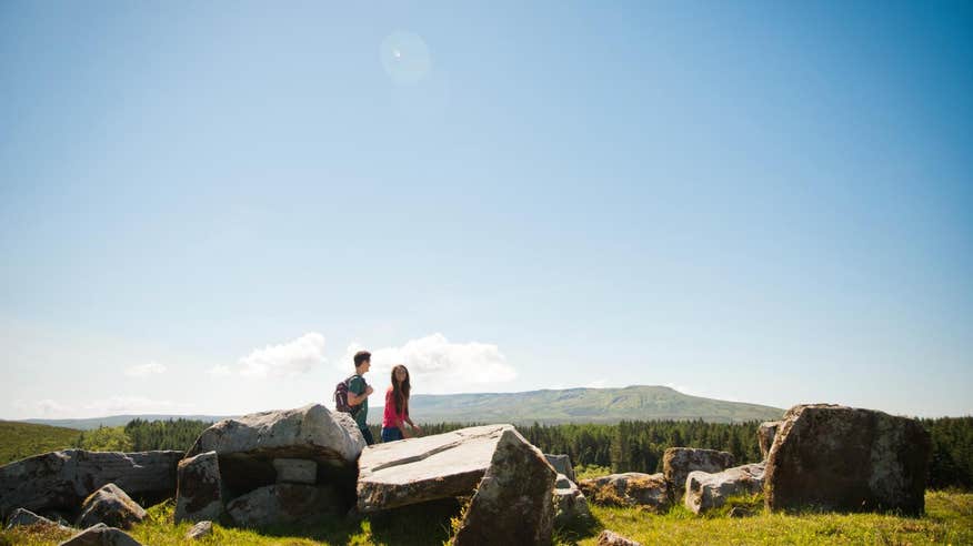 Man and woman walking through Cavan Burren Park on a sunny day