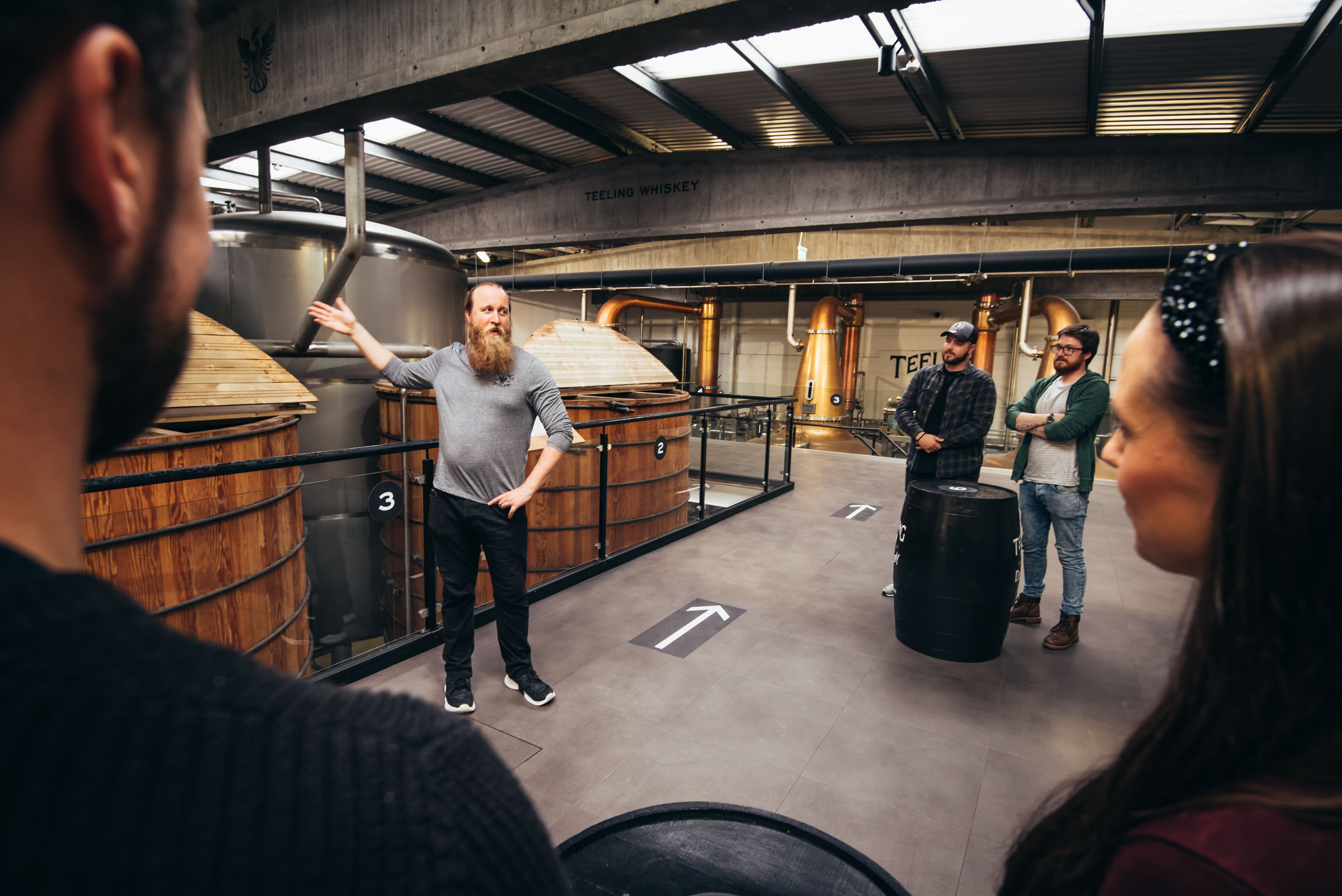 A guide giving a tour at Teeling Whiskey Distillery standing at one of the vats