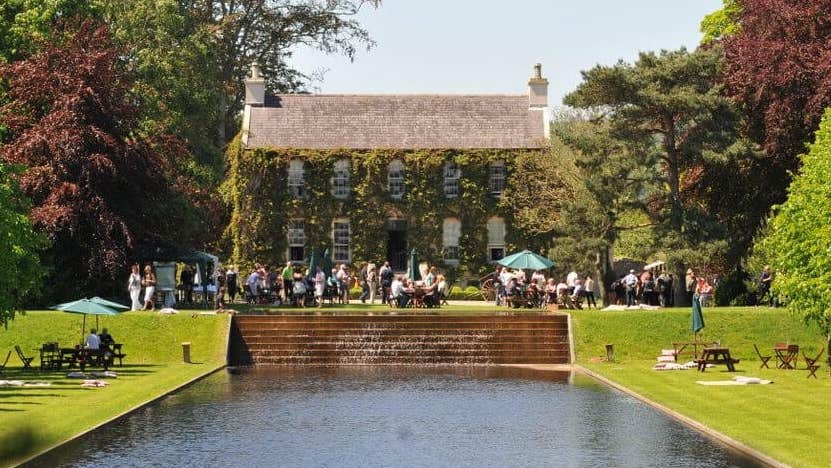 Festival of Gardens & Nature 2026, view across a man made square pond looking at an old house in the distance.