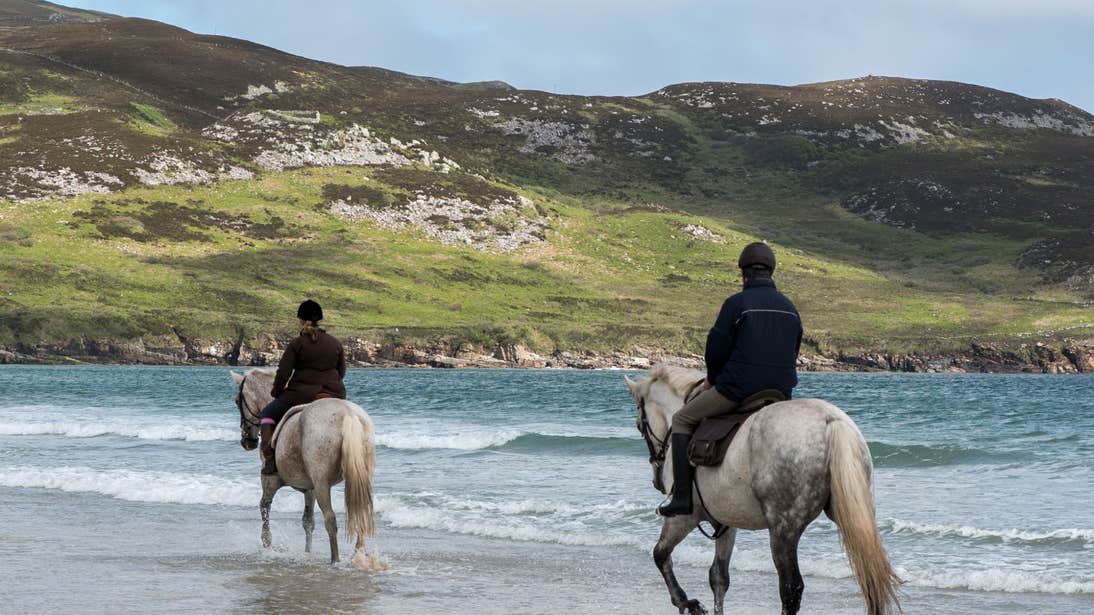 Two horse riders wading out into the water in Ards Forest, Donegal