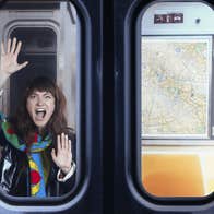 A woman is seen shouting through the window of a train with hands pressed flat against the glass