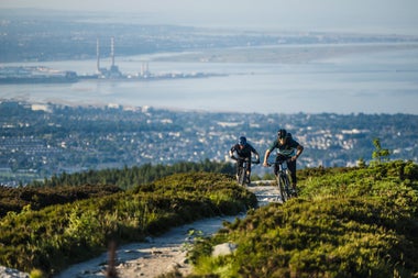 Two people on mountain bikes cycling up Ticknock mountain