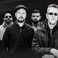 Group of 8 men in outdoor coats, some wearing sunglasses.