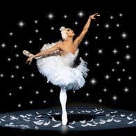 Les Ballets Trockadero de Monte Carlo, a person in a white tutu standing on point on one leg with the other stretched out behind them.