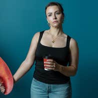 Ross and & Rachel by James Fritz, an unhappy looking woman with a takeout cup of coffee is holding the large claw of a large lobster.