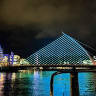 The Samuel Beckett Bridge viewed from one of the boats in the middle of the River Liffey. The bridge is illuminated on blue lights as part of a display.