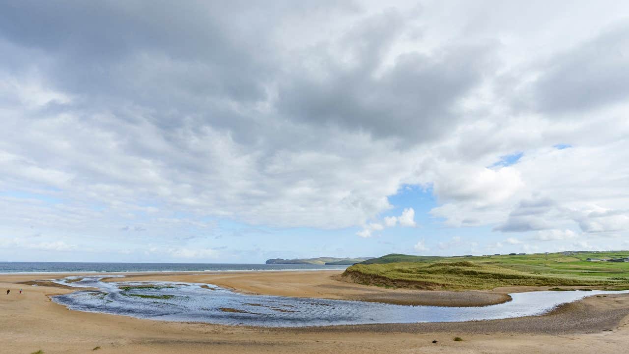 A sandy beach with an inlet of water in the middle