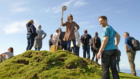 Lambay Nature Walking Tours group on a hill with one woman holding a decorated staff