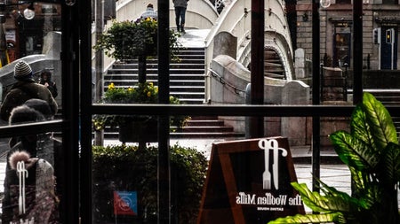 A seating area in a restaurant with old style windows with a view of a bridge