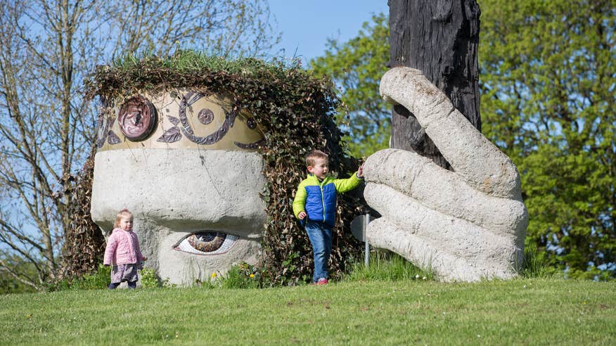 Two kids playing beside a sculpture in Dún na Sí Heritage Park in County Westmeath