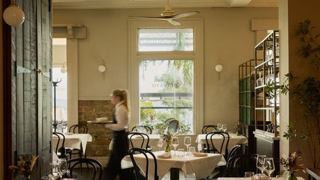 A bright dining space with large window in the background and a server working