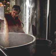 Someone pouring grains into a large vat in a brewery