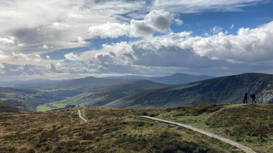 Two walkers on the Wicklow Way overlooking the Wicklow National Park.