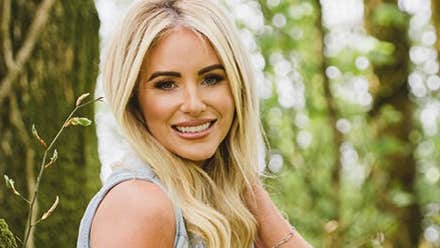 A smiling woman with blurry trees in the background.