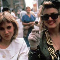 Two smiling women. One is dressed simply, the other boldly.