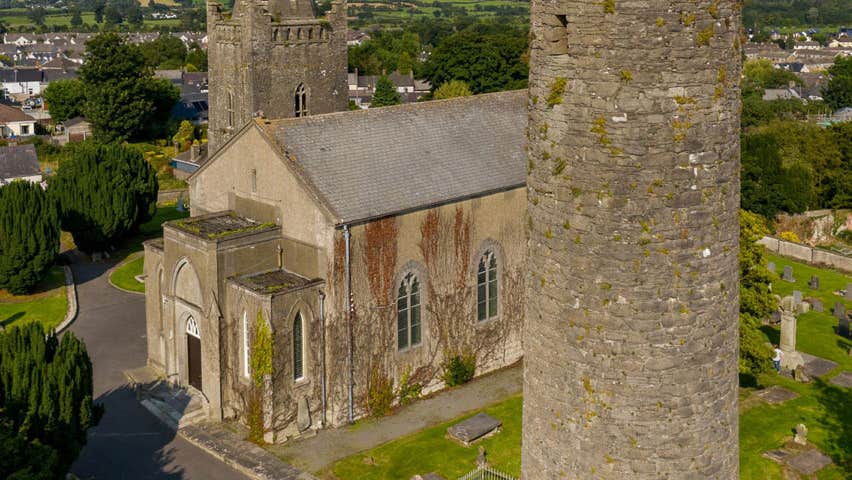 A church beside a round tower overlooking a town