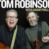 2 laughing older men both strumming guitars.