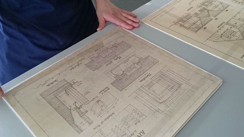 A person looking at some old building drawing plans