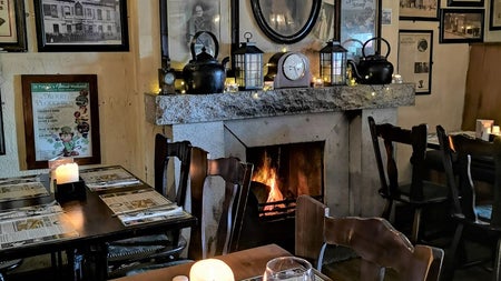 Interior of a traditional Irish pub with tables set for dinner by an open fire