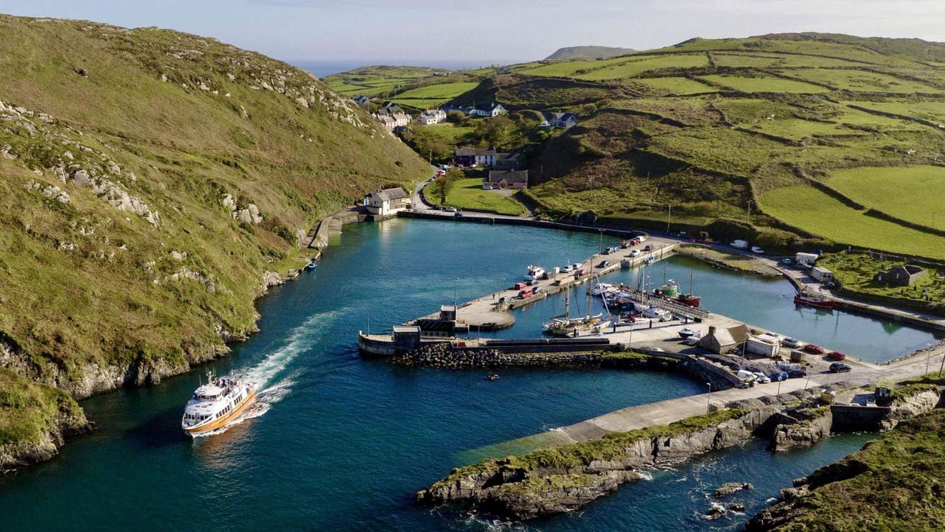 An aerial view of the pier at Cape Clear Island with a ferry sailing out
