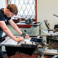 A person working at a screen printing station using a large manual press in a workshop