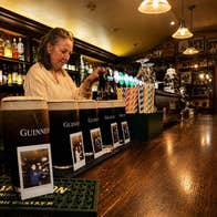 Pints of Guinness lined up on a bar each paired with a polaroid and a bar person pouring another one