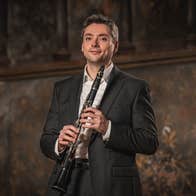 A slightly smiling man holding a clarinet
