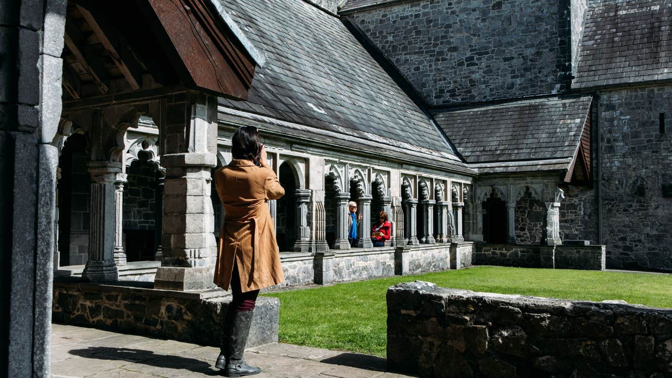 People standing beside grass outside an old stone building
