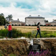Three people walking on a path in front of Castletown House, Co Kildare