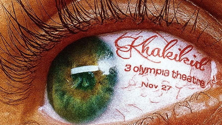 Very close up view of a green eye with long dark lashes and red text written in the white part of the eye