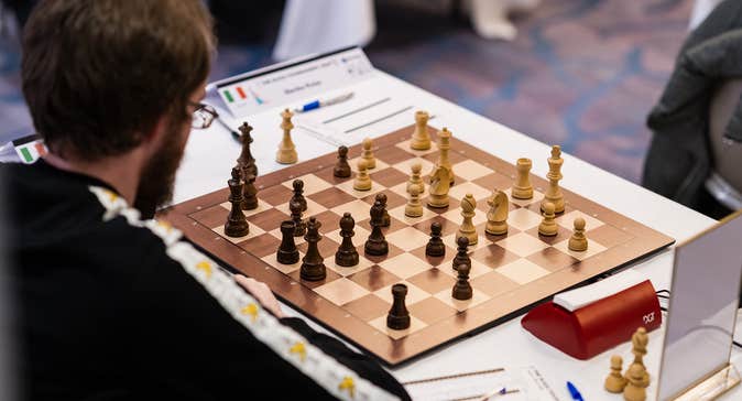Chess player at board analysing position as black
