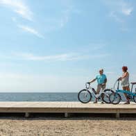 Two people with bikes on a boardwalk on a beach on a sunny day