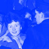 Blue and grey photo from 60s of happy young women waiting for an idol being held back by line of men