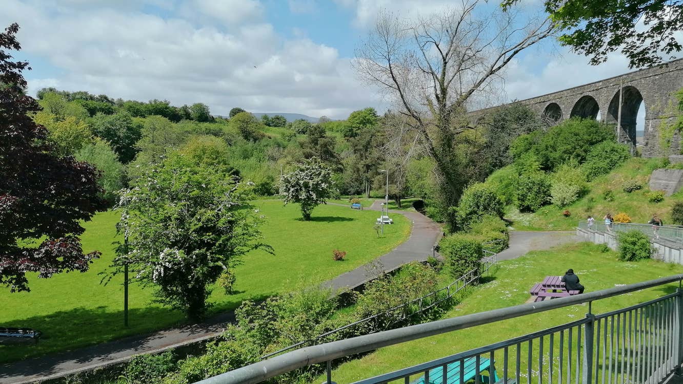 StepsBackThruTime Guided Walking Tour Experiences view of a park area overlooked by a grey stone bridge with arches