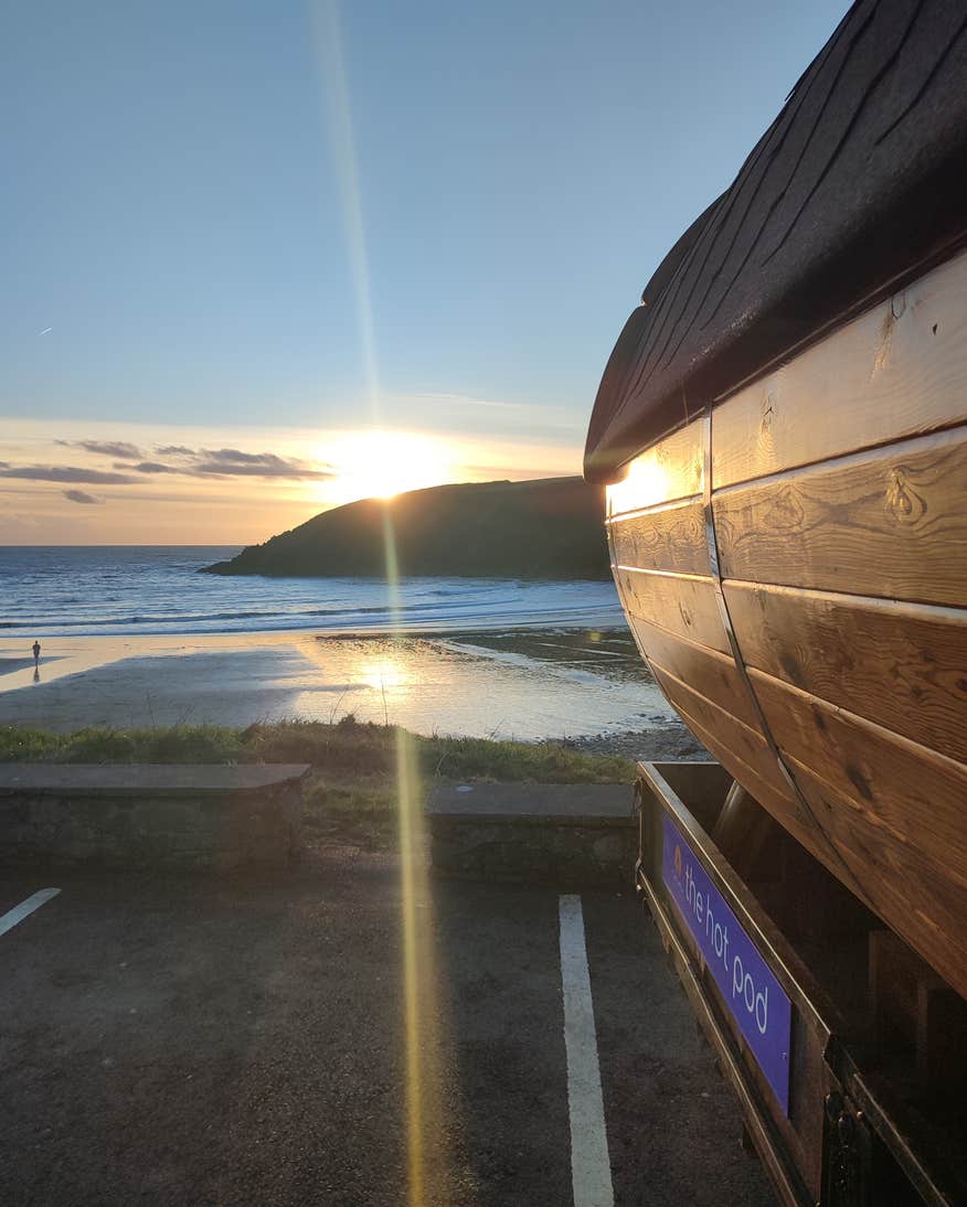 The sunsetting behind a mountain at Kilmurrin Cove in Waterford with The Hot Pod sauna.