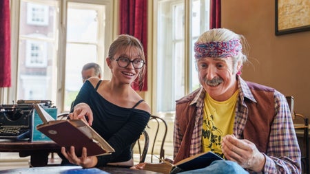 A lady poses with an open book beside a wax figure of Pat Ingoldsby