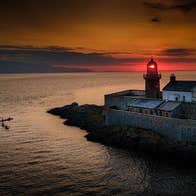 A view of Fenit Lighthouse at sunset with Wild Water Adventures