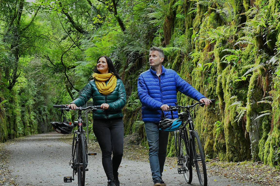 Man and woman walking their bikes through the Waterford Greenway 