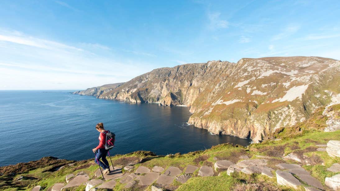 A woman walking across the Slieve League sea cliffs with an amazing view of the Atlantic Ocean