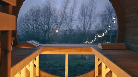 The view out of a sauna entrance with trees a string of lights