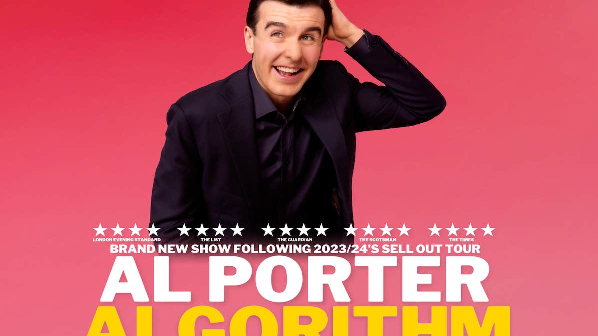 A laughing man in dark suit is scratching his head with left hand, against bright pink background.