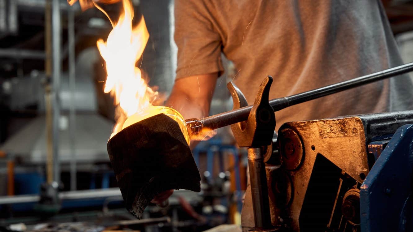 Person holding a piece of crystal on an iron poker over a large flame