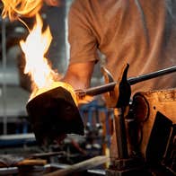 Person holding a piece of crystal on an iron poker over a large flame
