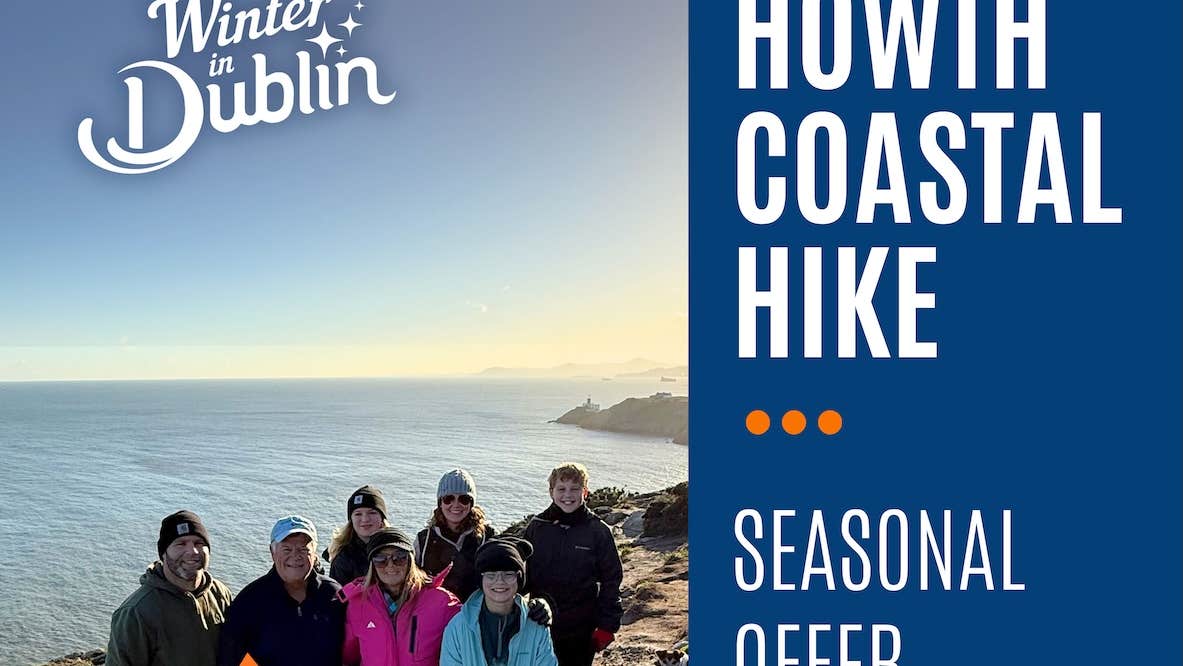 A group of smiling people outdoors with the sea in the background.