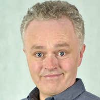 Comedian Patrick McDonnell, smiling looking slightly shocked.