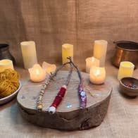 decorative wands sit on a wooden wedge with a hessian backdrop surrounded by candles